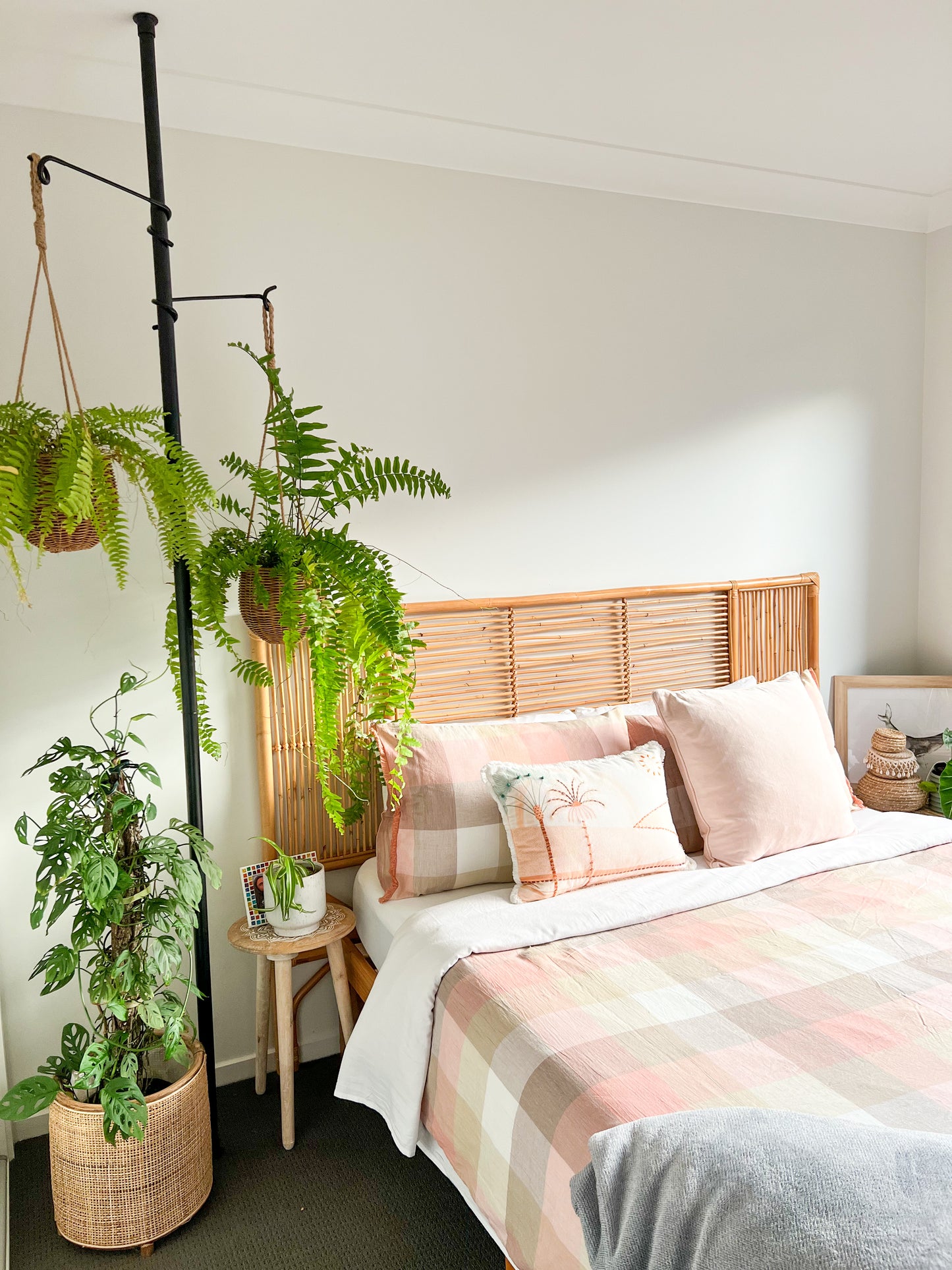 Tension plant pole with hanging planters featuring green ferns in bedroom